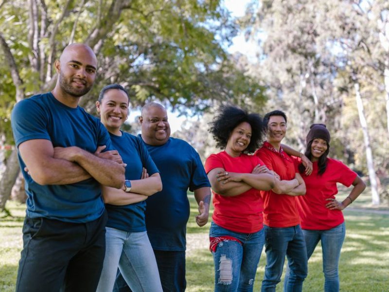 Conóceme Diverse group of adults bonding and enjoying team activity in a park.